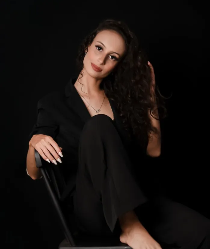 Chay Vitória sentada em uma cadeira, com fundo preto